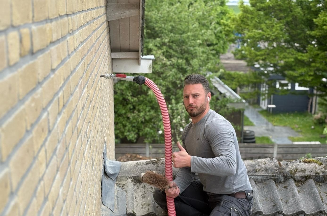 Een vakman van ons Jongejans-team brengt via een slang spouwmuurisolatie aan in een bakstenen woning
